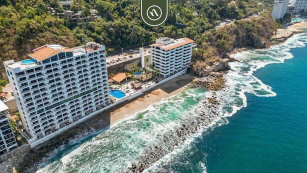 A coastal hotel with multiple balconies, a pool, and a beach view. - Beachfront Puerto Vallarta studio with pool, WiFi (Puerto Vallarta)