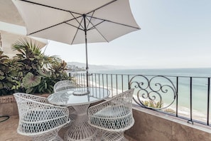 Un balcon avec une table et des chaises, donnant sur une plage.