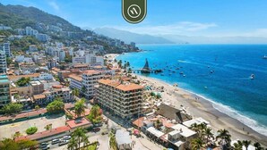 Un paisaje urbano costero con playa, edificios y barcos.
