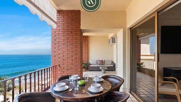 Un balcón con mesa lista para comer, con vistas al océano.