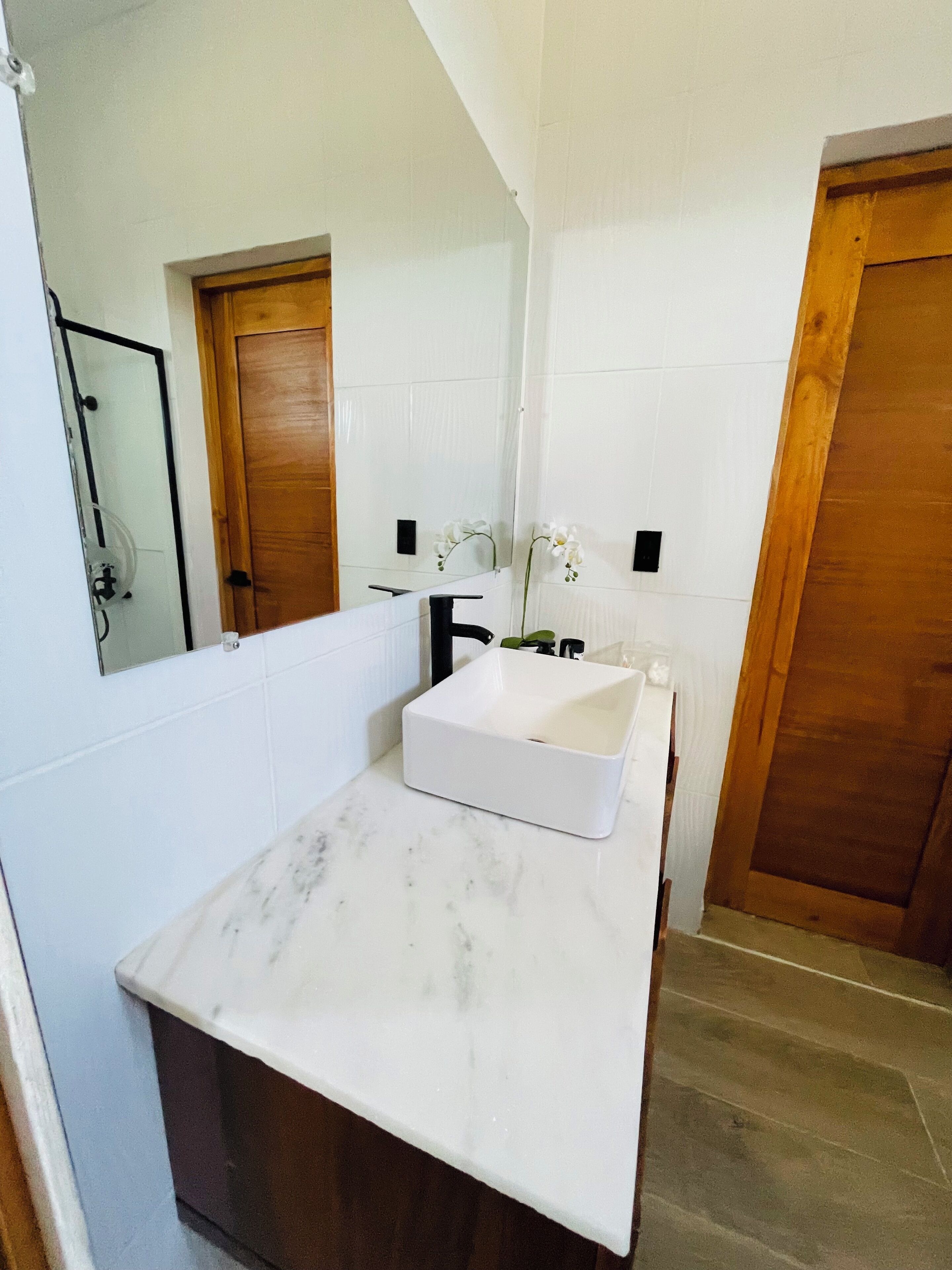 Un bagno con un lavandino bianco, uno specchio e porte in legno.