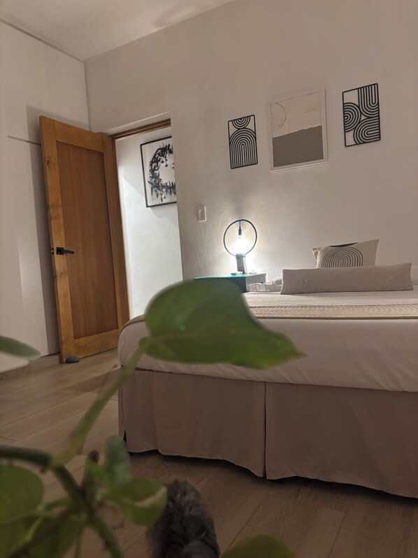 A bedroom with a bed, a bedside table with a lamp, and a door. - Villa Nola Montecristi (Monte Cristi)