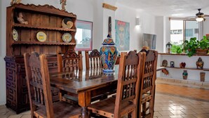 A dining area with wooden furniture, a decorative vase, and a wall with cultural artwork. - Puerto Vallarta 2BR/2BA | Beachfront Pool & Views (Puerto Vallarta)