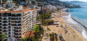 Un hotel frente al mar con varios balcones, una playa y un muelle.
