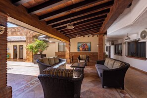 Ein Patio im Freien mit Korbmöbeln, Steinboden und Backsteinwand.