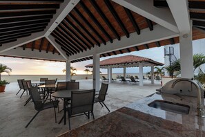 An outdoor patio with a grill, seating, and a view of the ocean.