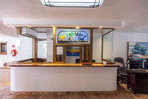 Een receptiebalie met een bord waarop 'Vista del Sol' staat, een brandblusser en een schilderij aan de muur.