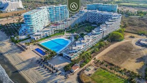 Un gran complejo turístico con varias edificaciones, una piscina central y una zona de playa.