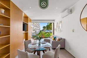 Une chambre d’hôtel moderne avec un coin repas, un canapé et une vue sur les palmiers.