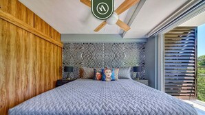 A bedroom with a large bed, a ceiling fan, and a geometric patterned wall. - Sea View Residences 302 | 2BR/2BA PV | Pool & Beach (Puerto Vallarta)