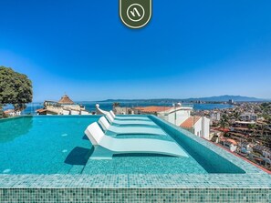 Ein Rooftop-Infinity-Pool mit freiem Blick auf Stadt und Meer.