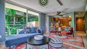 A modern living room with a sofa, a coffee table, and a patterned rug. There is a dining area with a table and chairs in the background. - Sea View Residences 302 | 2BR/2BA PV | Pool & Beach (Puerto Vallarta)