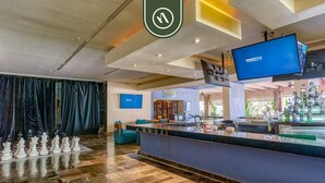 Un área de bar con un tablero de ajedrez, un televisor que muestra DIRECTV y una barra con diversos artículos.