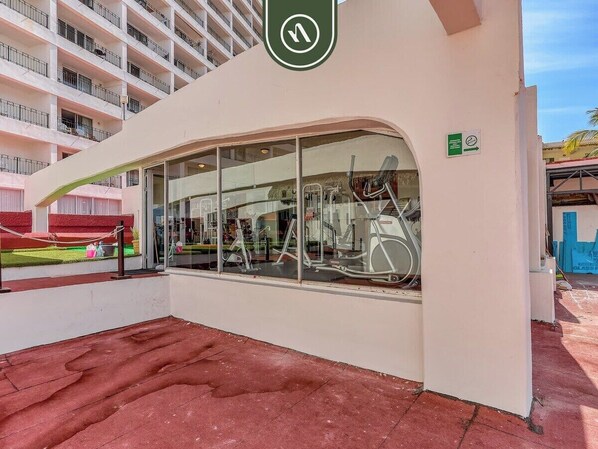 A modern building with a large glass window, a green sign with a white arrow, and a red floor.