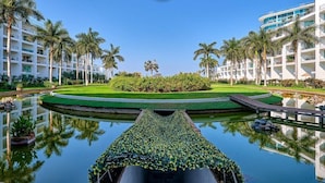 Un hotel con piscina, palmeras y un césped bien cuidado.