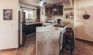 Una cocina con una isla de mármol, gabinetes de madera oscura, una estufa a gas y una pata de gallo.
