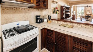 Eine Küche mit Herd, Backofen, Kaffeemaschine und einem Essbereich mit Tisch und Stühlen.