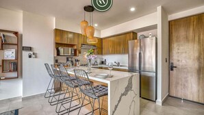 A modern kitchen with a marble island, stainless steel appliances, and a wooden cabinet. - Serenity 301 | 2BR Puerto Vallarta | Rooftop Pool (Puerto Vallarta)