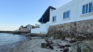 Un edificio costero con pared de piedra y techo de paja.