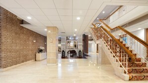 A spacious lobby with a marble floor, a wooden reception desk, and a staircase with ornate railings. - Charming 1-bedroom condo in the heart of  Miami Beach (Miami)