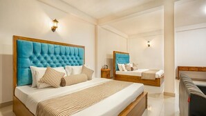 A hotel room with two beds, each with a tufted headboard, a wooden bench, and a small bedside table. - Ella Ostella (Ella)