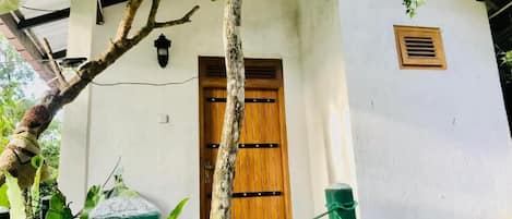 Un edificio blanco con puerta de madera y una ventana pequeña.