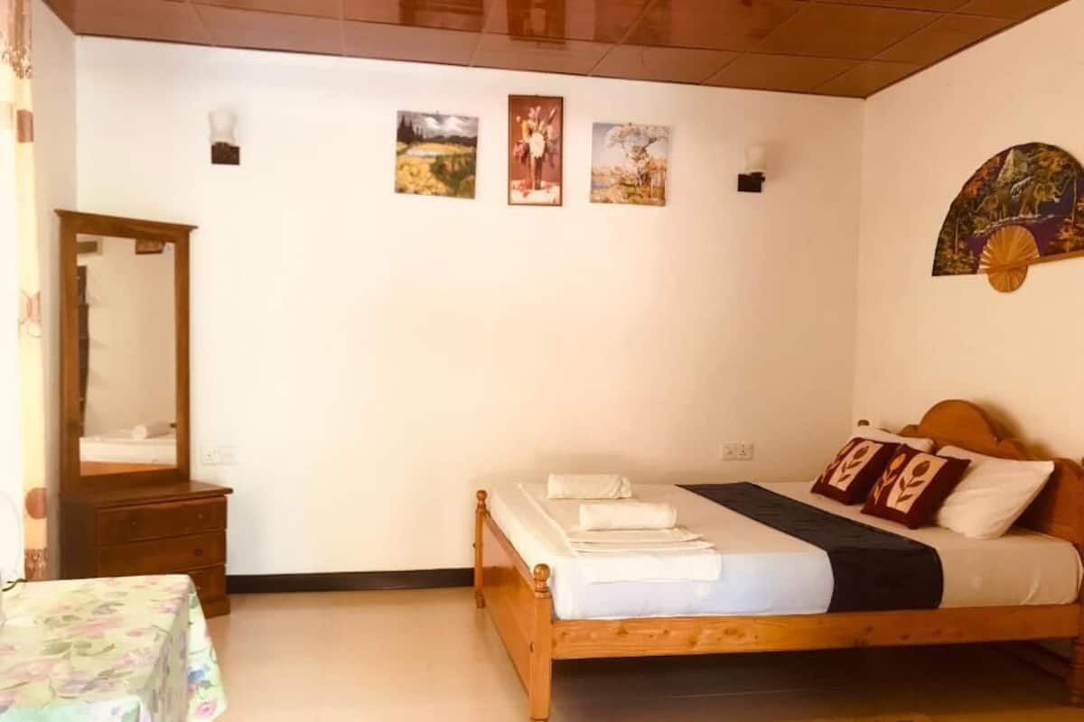 A bedroom with a wooden bed, a mirror, and four framed pictures on the wall.
