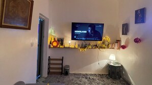 A living room with a television, a sofa, a small table, and a decorative shelf.