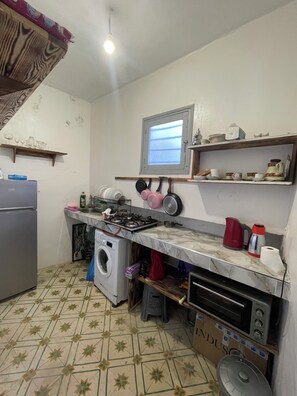 A kitchen with a washing machine, a microwave, a gas stove, and various kitchen utensils on the counter. - Cozy hostel in the heart of Medina Rabat (Rabat)
