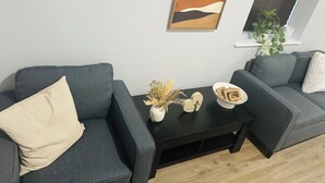 A modern living room with two grey sofas, a black coffee table, and a framed abstract painting on the wall. - Exquisite private 1-bedroom apartment in delightful Newark with modern amenities (Newark)