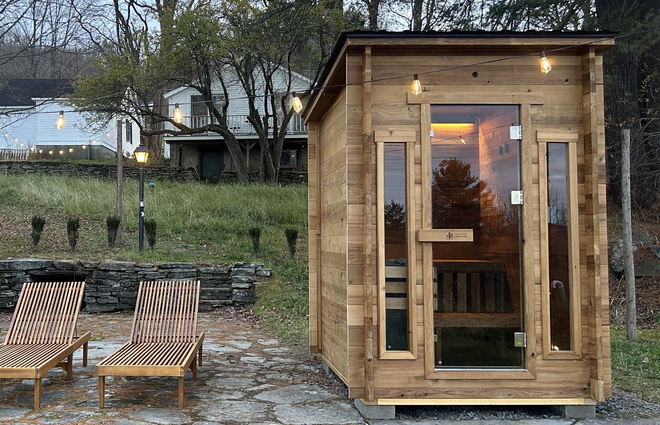 Eine Holzhütte mit Glastür, zwei Lounge-Sesseln und Lichterkette.