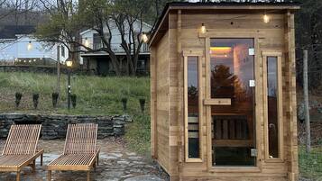 Eine Holzhütte mit Glastür, zwei Lounge-Sesseln und Lichterkette.