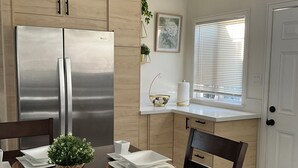 A modern kitchen with stainless steel appliances, wooden cabinets, and a dining area set for four.