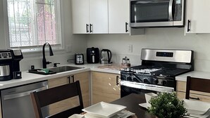 A modern kitchen with white cabinets, a stainless steel microwave, a gas stove, and a dishwasher.