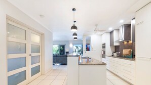A modern kitchen with white cabinetry, a central island, and a dining area visible in the background.