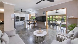 A modern kitchen with a central island, bar stools, and a dining area with a table and chairs.