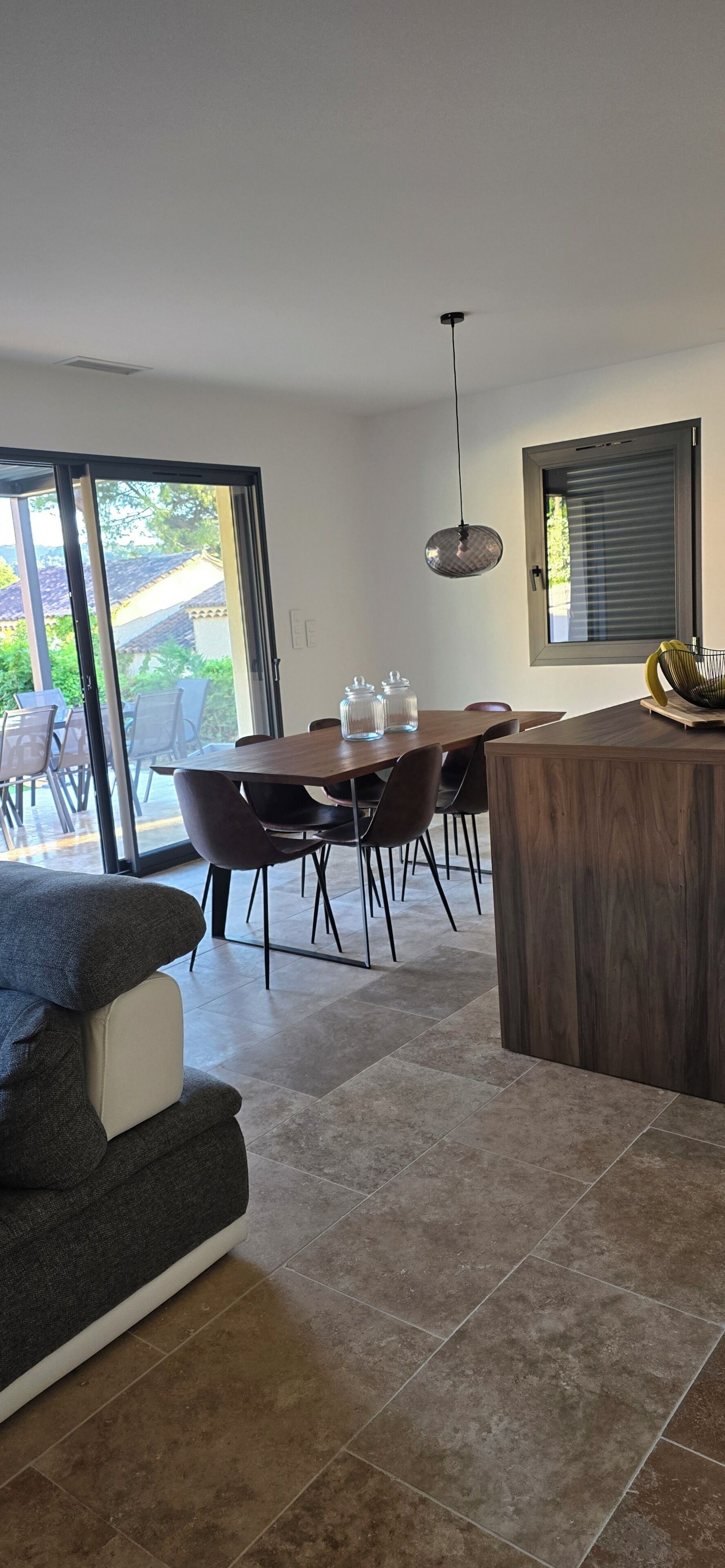 A modern living room with a dining area, large windows, and a view of the outdoors.