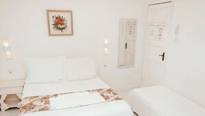 Een hotelkamer met een bed, nachtkastjes, een deur en een wandlamp.