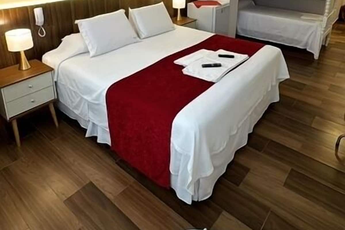 A hotel room with a large bed, a smaller bed, a desk, and a chair.