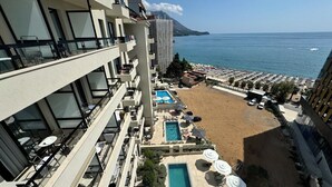 A hotel with a pool, outdoor seating, and a view of the sea.