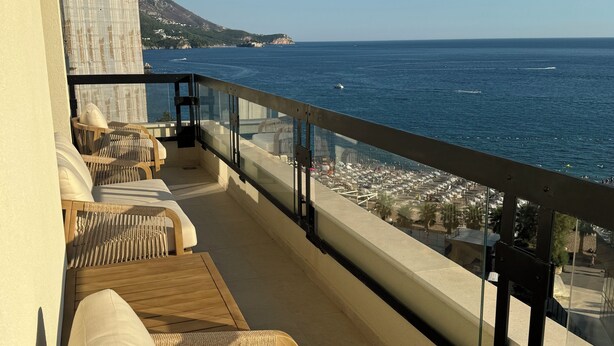 A balcony with wicker furniture and a view of the sea.