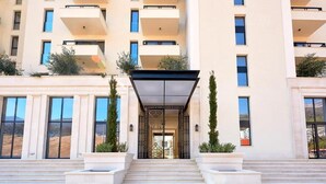 A modern hotel entrance with a covered walkway, large windows, and a symmetrical facade.