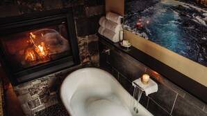 Ein Badezimmer mit Steinwand, Badewanne, Kamin und Handtuchhalter an der Wand.