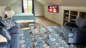 A bedroom with a bed, a sofa, a coffee table, and a TV on the wall. - DFW Hideaway located right off I-35W and near so many area attractions! (Argyle)