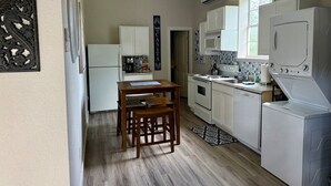 A compact kitchen with white cabinets, a wooden table, and a washing machine. - DFW Hideaway located right off I-35W and near so many area attractions! (Argyle)