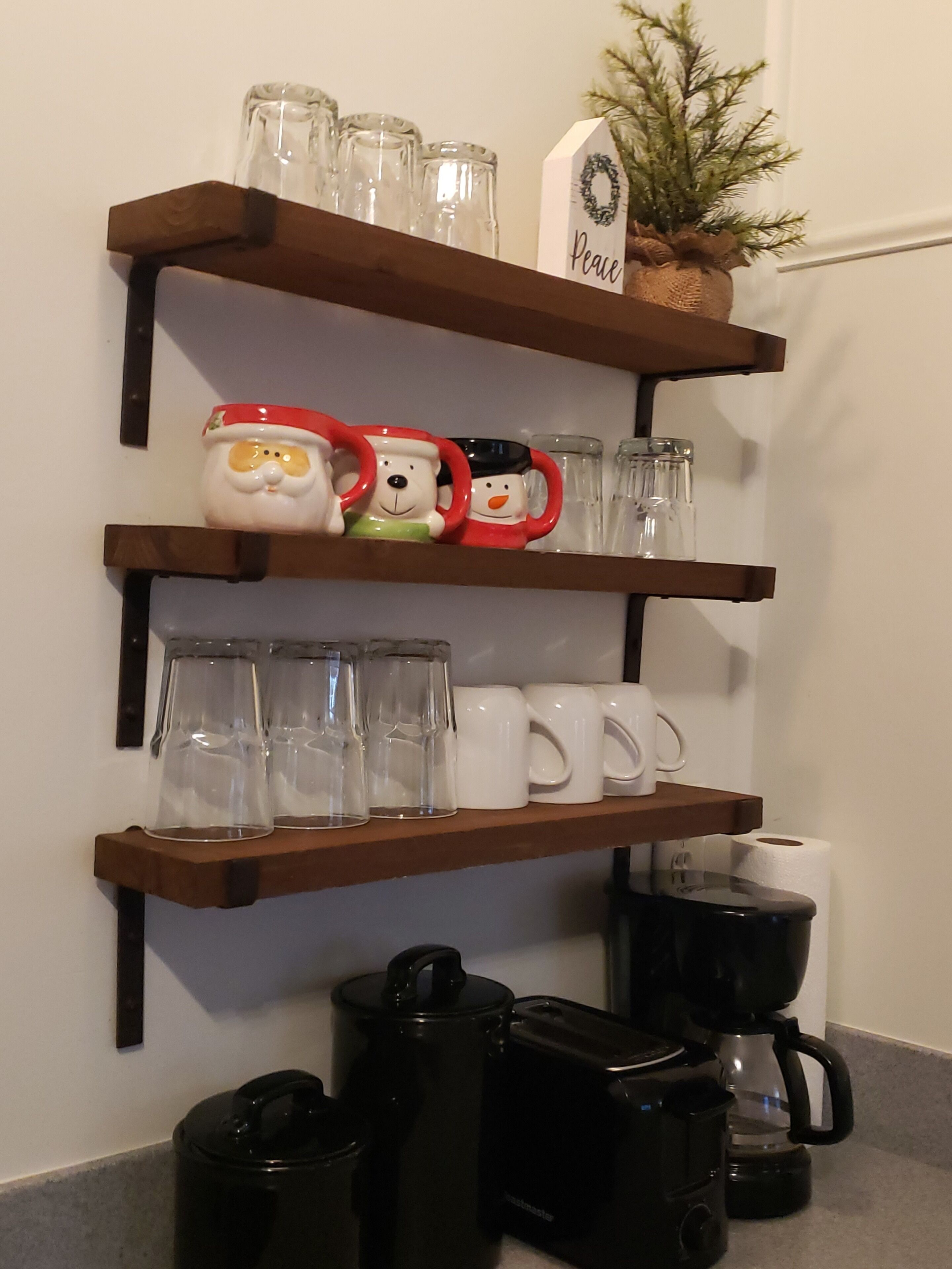 Keittiöalue, jossa on hyllyjä, joilla säilytetään lasiastioita, mukeja ja kahvinkeitintä.