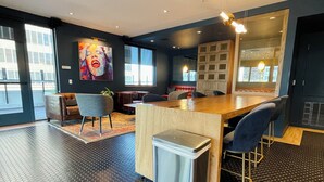 A modern interior with a hexagonal floor pattern, a central bar area, seating arrangements, and large windows providing natural light.