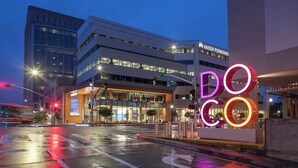 A modern building with a glass facade and a neon sign reading "DOCO".