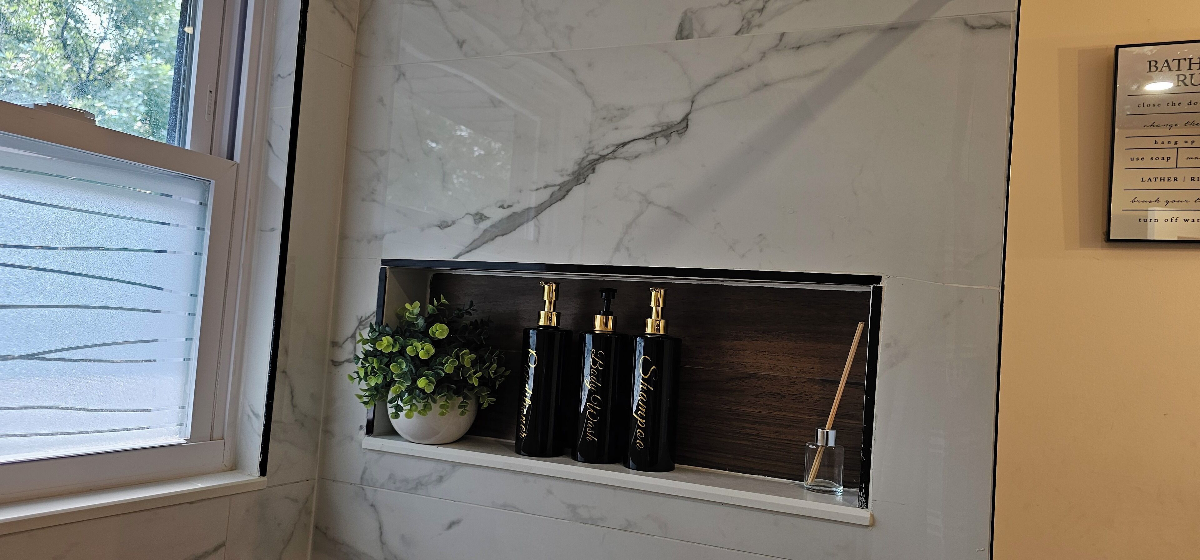 A bathroom vanity with a marble backsplash, a potted plant, and toiletries.