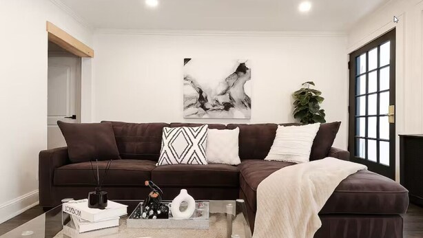 Ein modernes Wohnzimmer mit einem dunkelbraunen Sofa, einem Glastisch und einem großen, abstrakten Gemälde an der Wand.